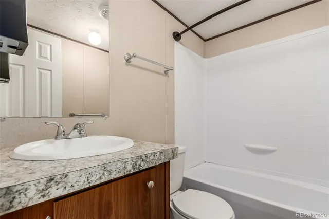 a bathroom with a granite countertop sink toilet and shower