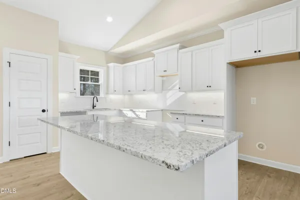 a kitchen with kitchen island granite countertop a sink and white cabinets