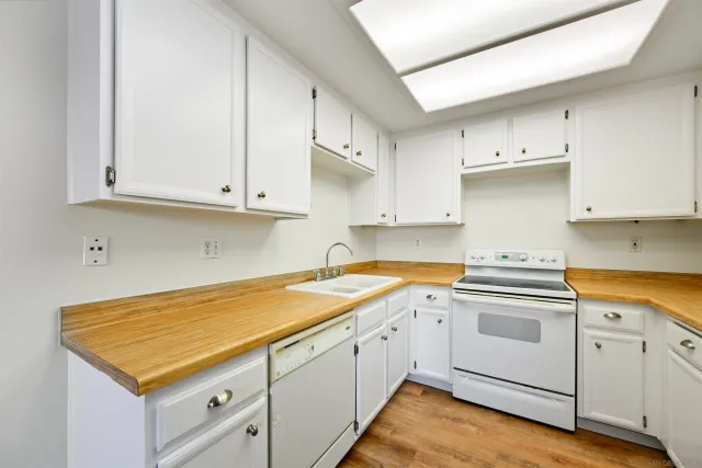 a kitchen with granite countertop white cabinets and white appliances