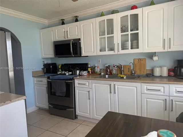 a kitchen with stainless steel appliances granite countertop a refrigerator a stove a sink and white cabinets