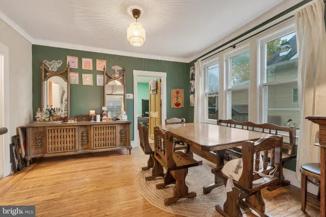 a dining room with wooden floor and a floor to ceiling window
