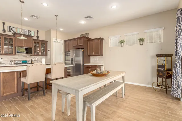 a kitchen with stainless steel appliances a stove a sink a refrigerator and chairs