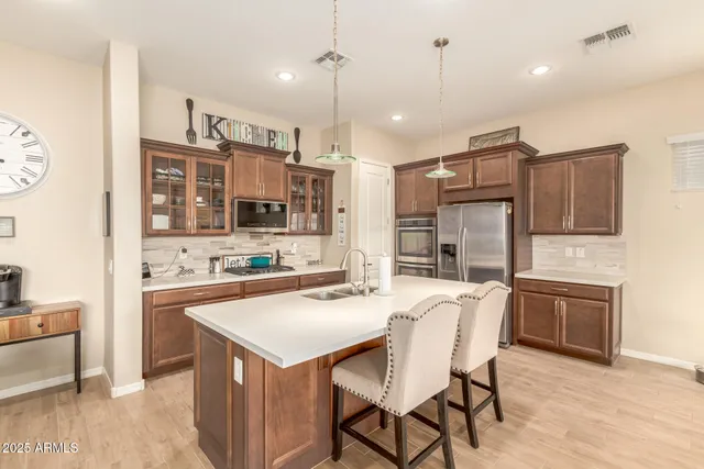 a kitchen with stainless steel appliances granite countertop a stove a sink a oven a refrigerator a oven a kitchen island with a refrigerator and chairs
