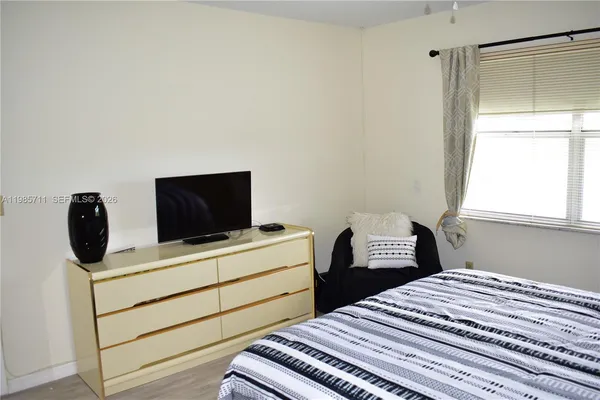 a bedroom with a bed and a flat tv screen on the dresser