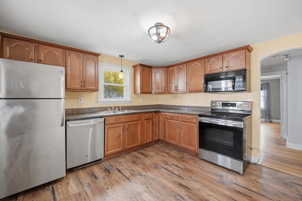 803 Armory Street Springfield, MA 01107 - Photo 13 of 34 a kitchen with stainless steel appliances granite countertop a stove a sink dishwasher a refrigerator and a microwave oven with wooden floor