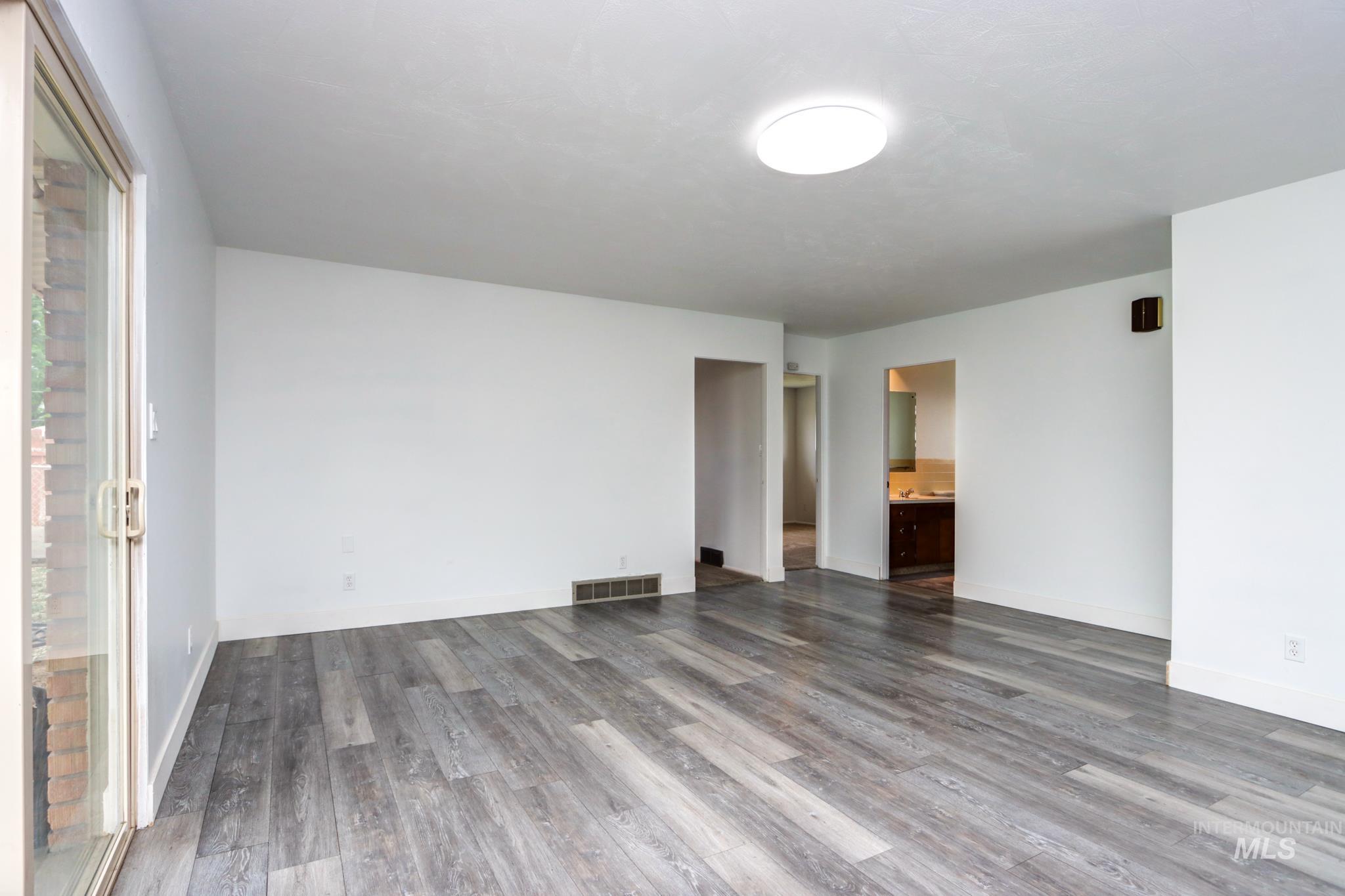 801 Thompson Avenue Nyssa, OR 97913 - Photo 7 of 46 Spacious interior with gray wood-finish flooring, white walls, and a contemporary ceiling light fixture