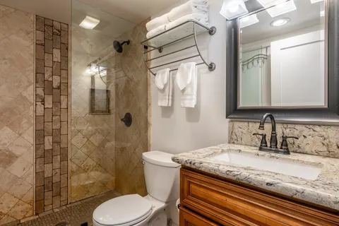 a bathroom with a granite countertop sink toilet a mirror and shower