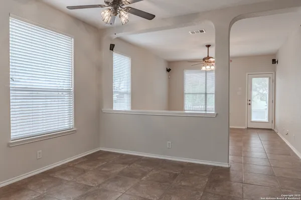 an empty room with wooden floor cabinet and windows
