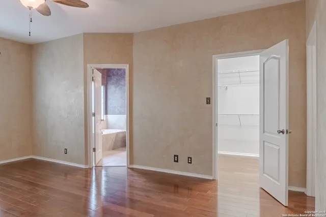 an empty room with wooden floor and chandelier fan