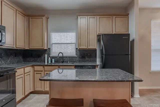a kitchen with stainless steel appliances granite countertop a refrigerator and a stove top oven