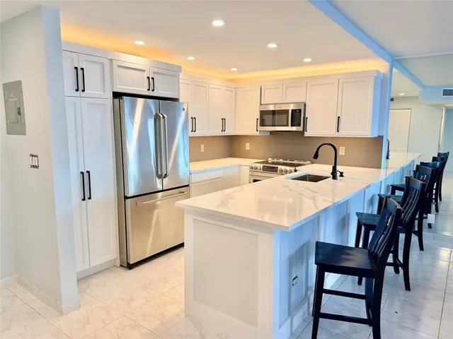 a kitchen with stainless steel appliances kitchen island granite countertop a stove a sink a table and chairs