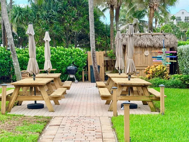 a view of a patio with table and chairs potted plants and large tree
