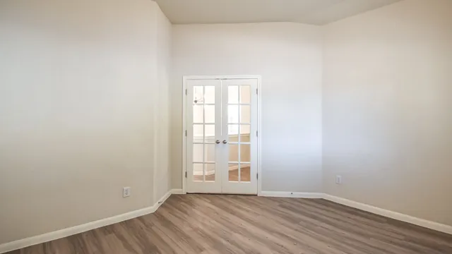 a view of an empty room with wooden floor and a window