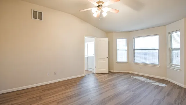 an empty room with wooden floor and windows