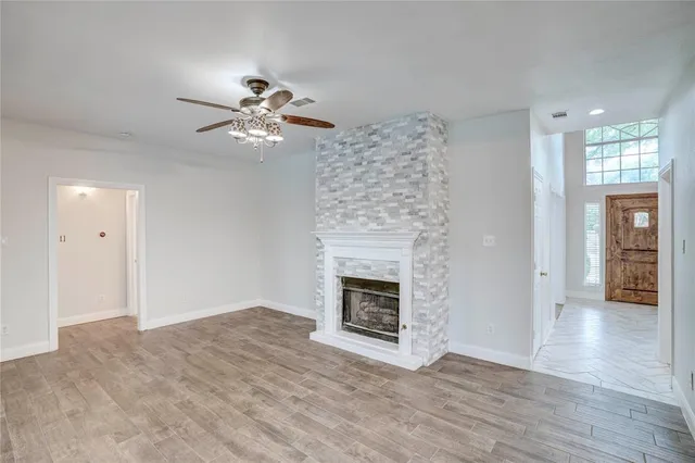 a view of a livingroom with a fireplace a chandelier fan and wooden floor