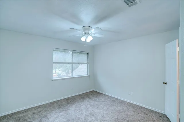 an empty room with chandelier fan and windows