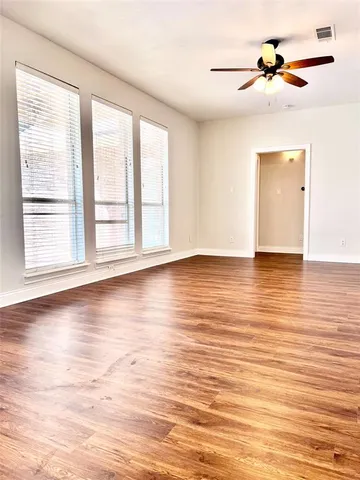 a view of empty room with wooden floor and fan