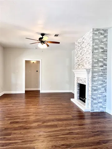 a view of a livingroom with a fireplace a ceiling fan and wooden floor