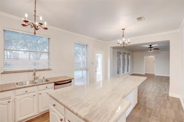 a view of a kitchen with granite countertop stainless steel appliances a sink stove and wooden floor