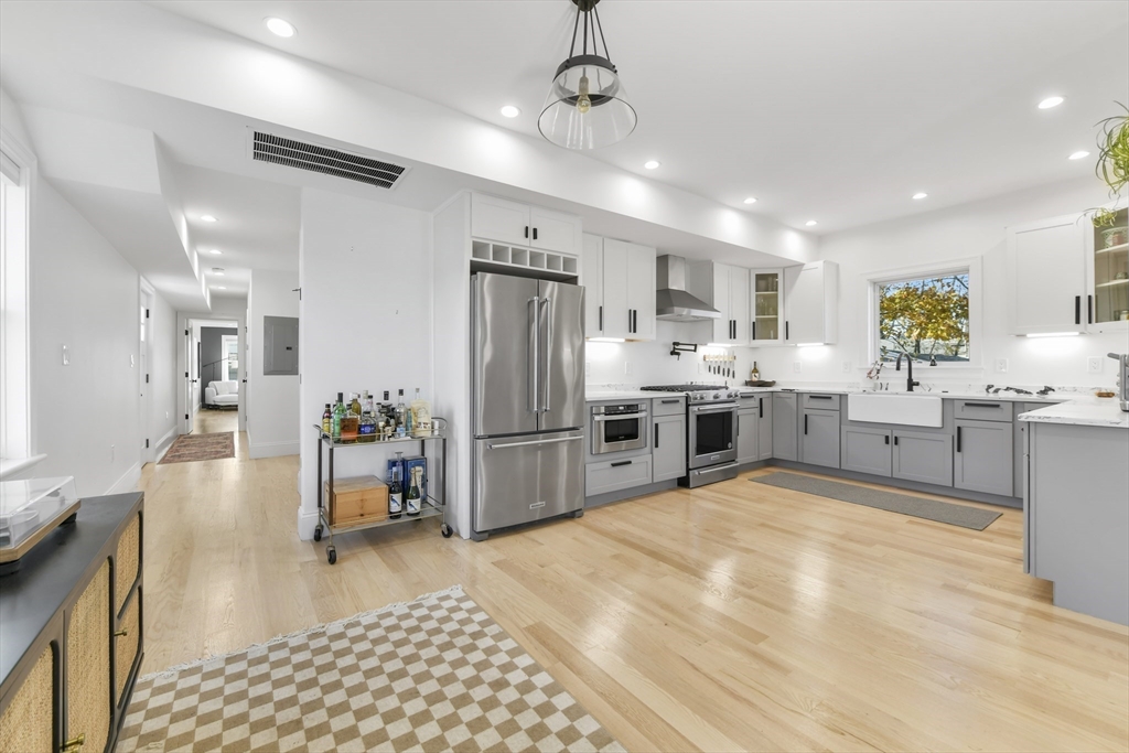 17 Akron Street, Unit 2 Boston, MA 02119 - Photo 7 of 25 a kitchen with stainless steel appliances a refrigerator a sink dishwasher a oven with white cabinets and wooden floor