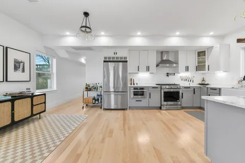 a large kitchen with stainless steel appliances kitchen island a large counter top and a view of living room
