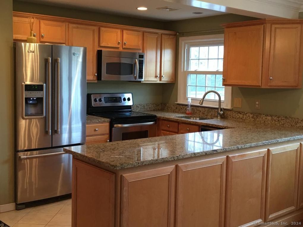 a kitchen with granite countertop stainless steel appliances a refrigerator microwave and sink