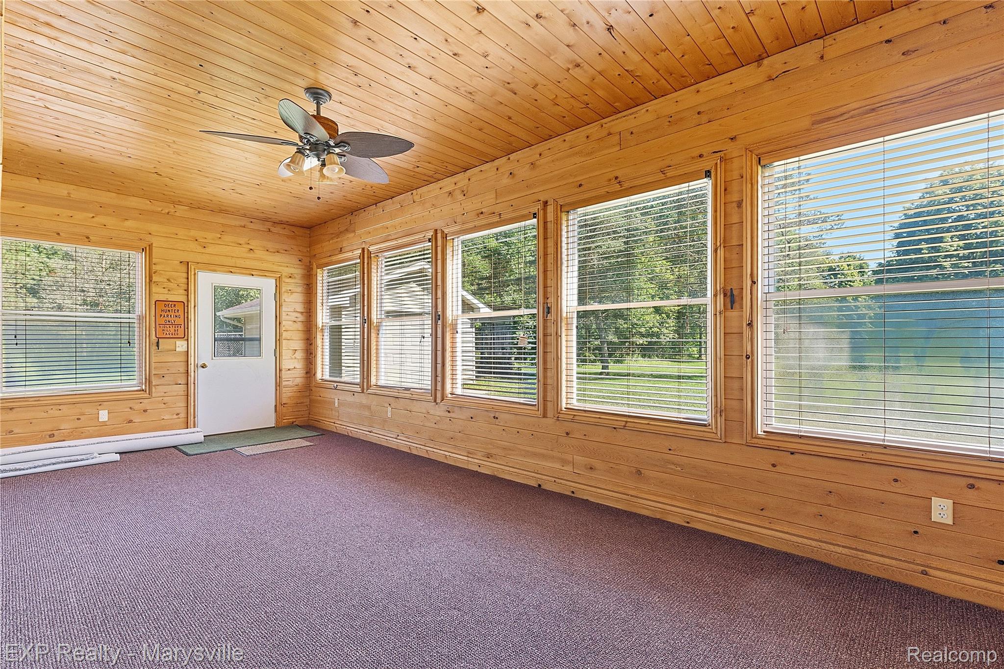 13739 Yale Road Yale, MI 48097 - Photo 16 of 50 Wood-paneled room featuring multiple windows, a ceiling fan, and a white door with a glass insert
