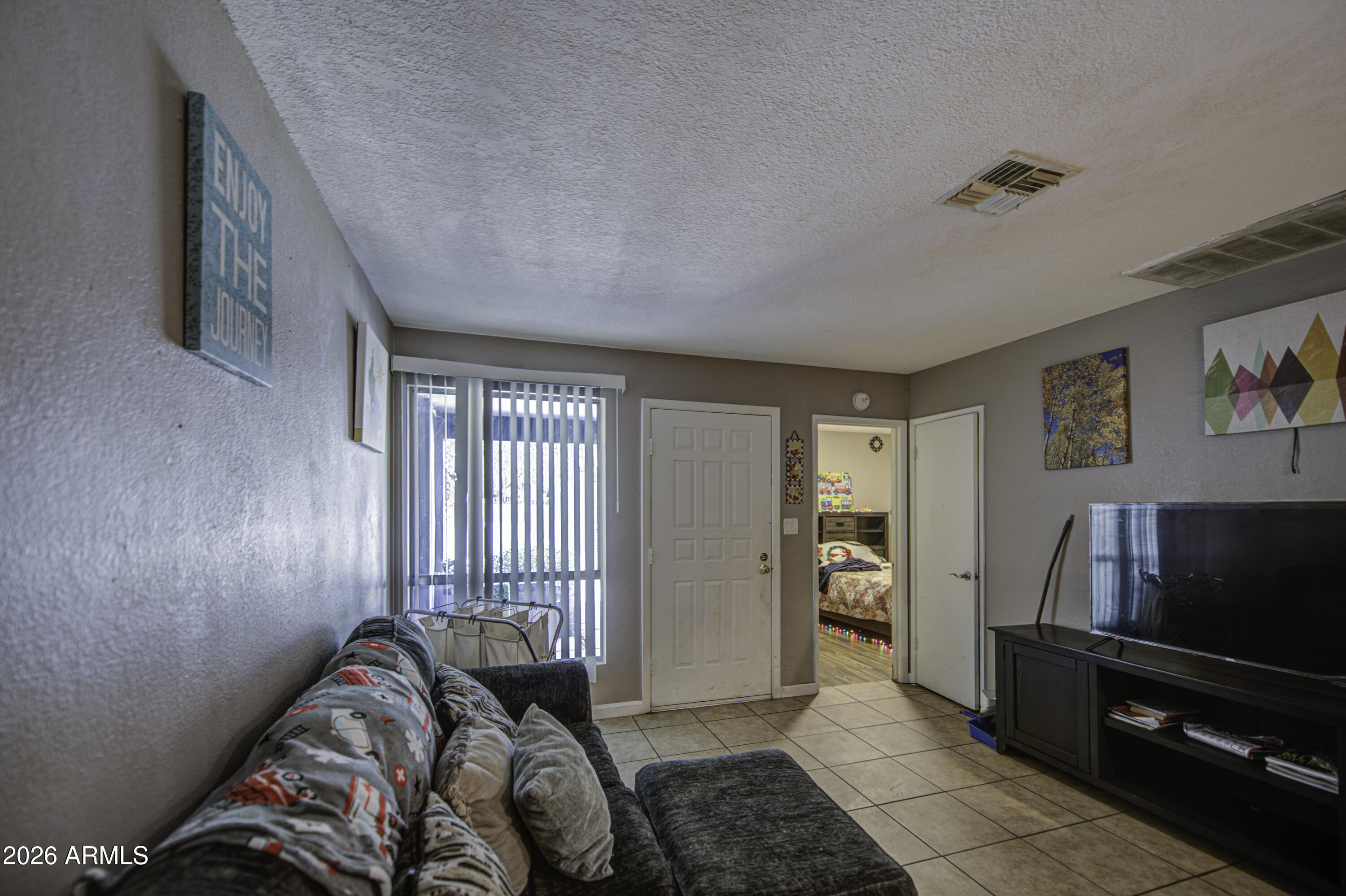 9009 West Elm Street, Unit 6 Phoenix, AZ 85037 - Photo 6 of 23 a bedroom with furniture and a flat screen tv