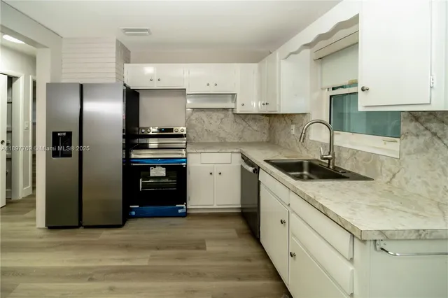 a kitchen with stainless steel appliances granite countertop a refrigerator and a sink