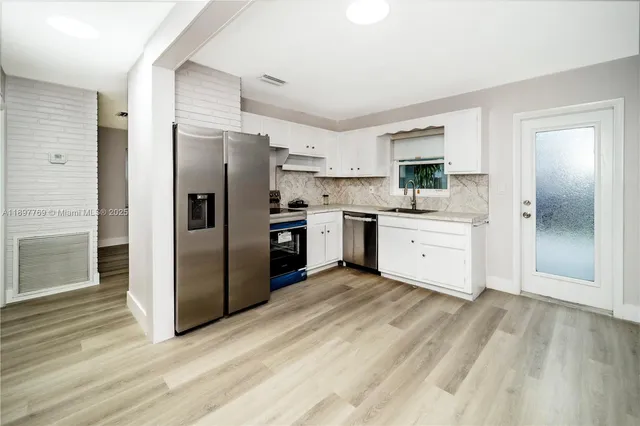 a kitchen with stainless steel appliances granite countertop a refrigerator and a stove top oven