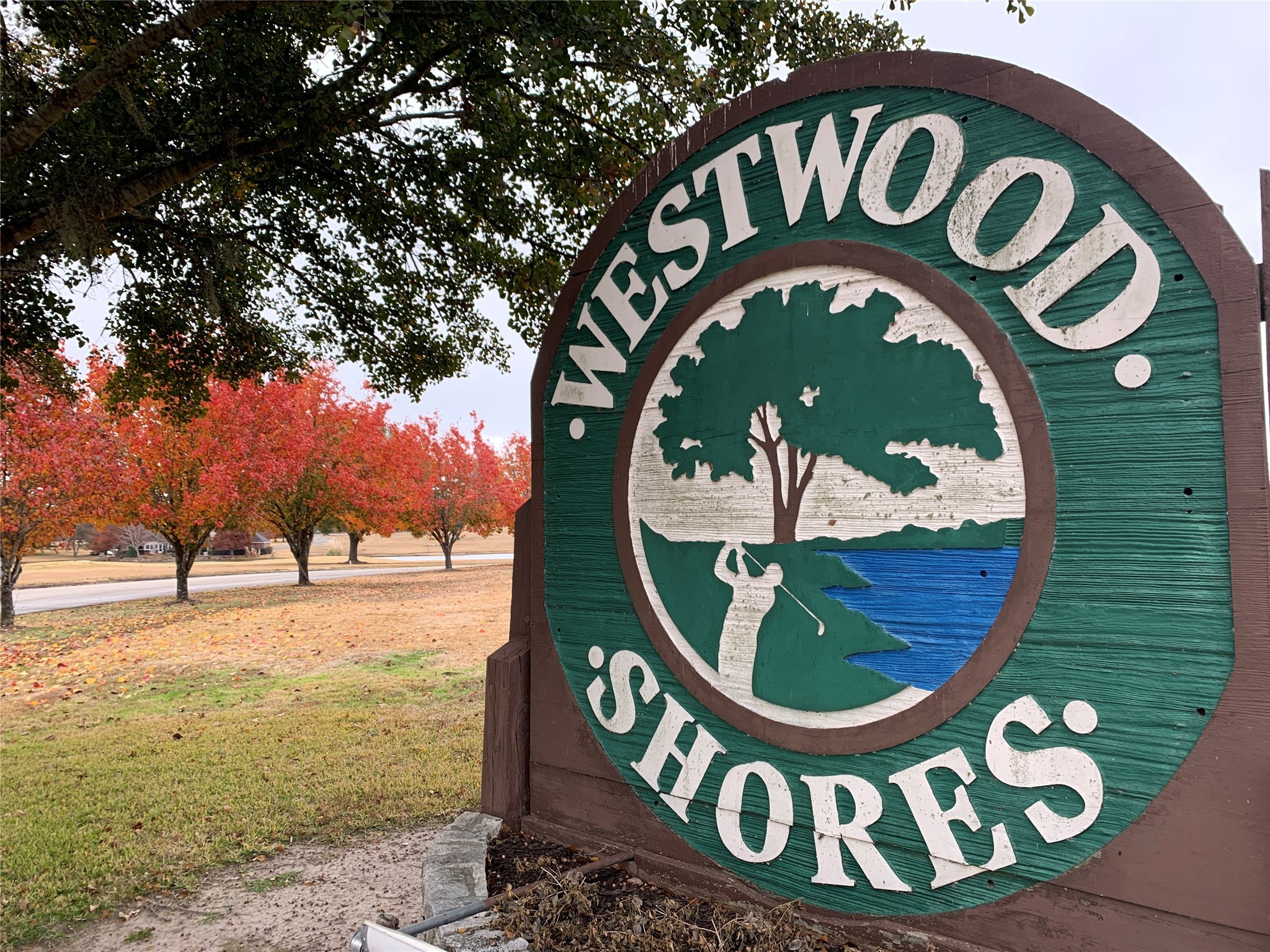 106 Westlake Road Trinity, TX 75862 - Photo 36 of 36 This photo shows the entrance sign for Westwood Shores, indicating a neighborhood with scenic surroundings. The area features vibrant trees and a golf-themed emblem, suggesting recreational opportunities and natural beauty.