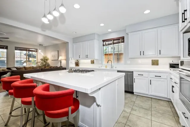 a kitchen with stainless steel appliances granite countertop a sink dishwasher and a stove with chairs