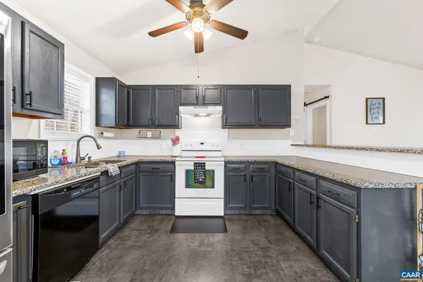 a living room with granite countertop kitchen island stainless steel appliances furniture a dining table and a chandelier
