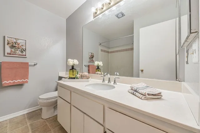 a bathroom with a granite countertop sink a toilet and a mirror
