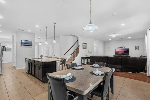 a open kitchen with stainless steel appliances kitchen island granite countertop a dining table chairs and stove top oven