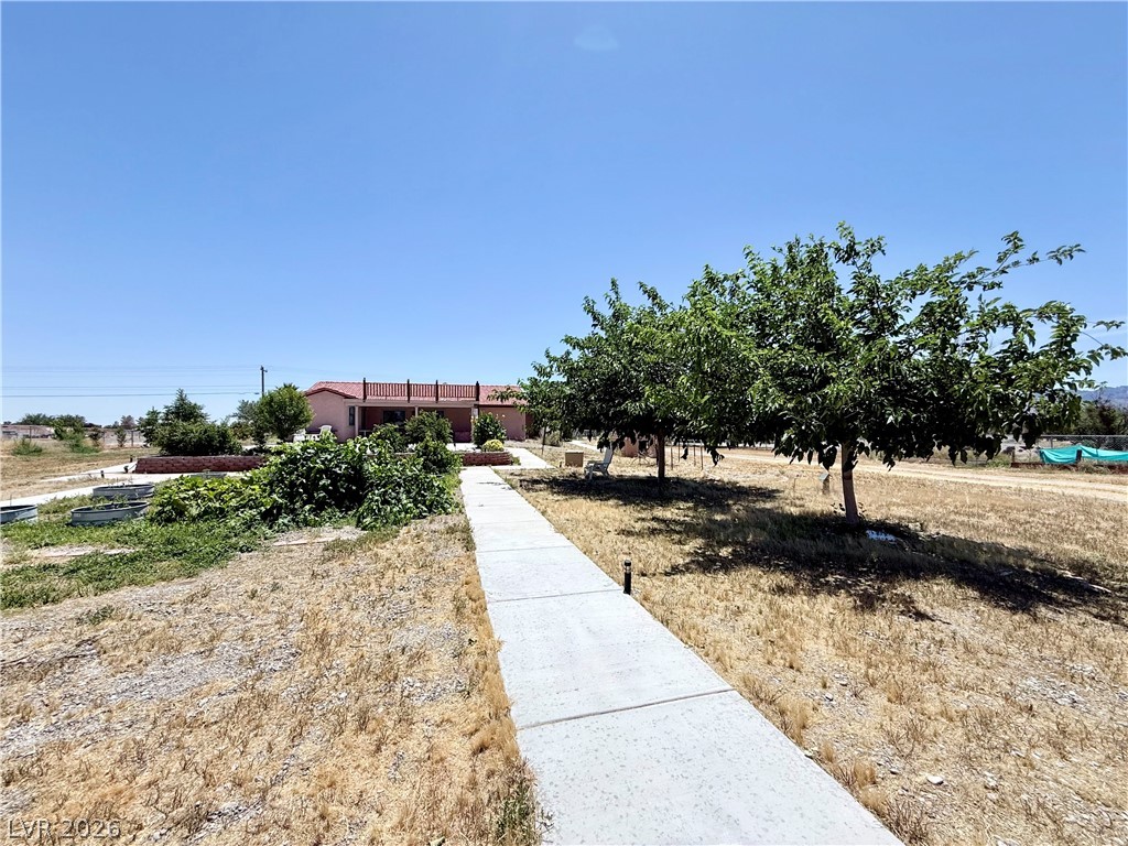 1220 East Gamebird Road Pahrump, NV 89048 - Photo 25 of 49 A welcoming walkway leads to this charming desert home, framed by mature trees.