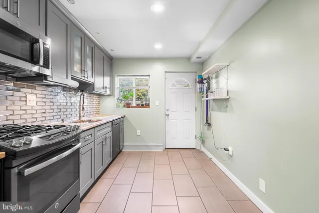 a kitchen with a sink a stove top oven and cabinetry