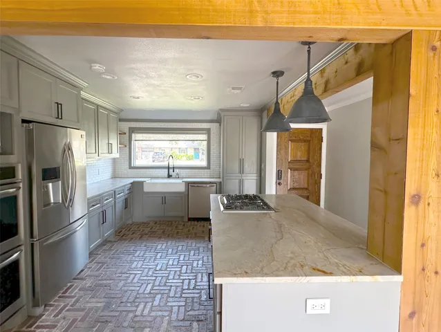 a kitchen with stainless steel appliances granite countertop a refrigerator a sink a stove and white cabinets