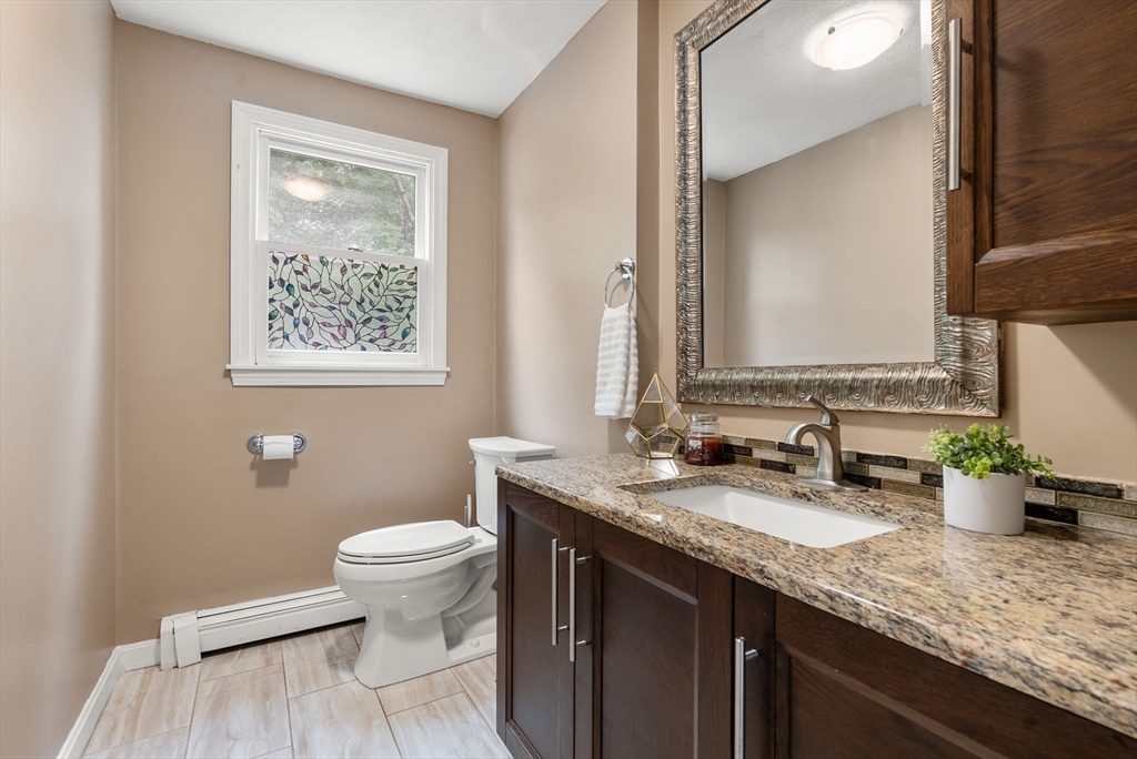 226 Pine Hill Circle Waltham, MA 02451 - Photo 13 of 28 a bathroom with a granite countertop sink a toilet and a mirror