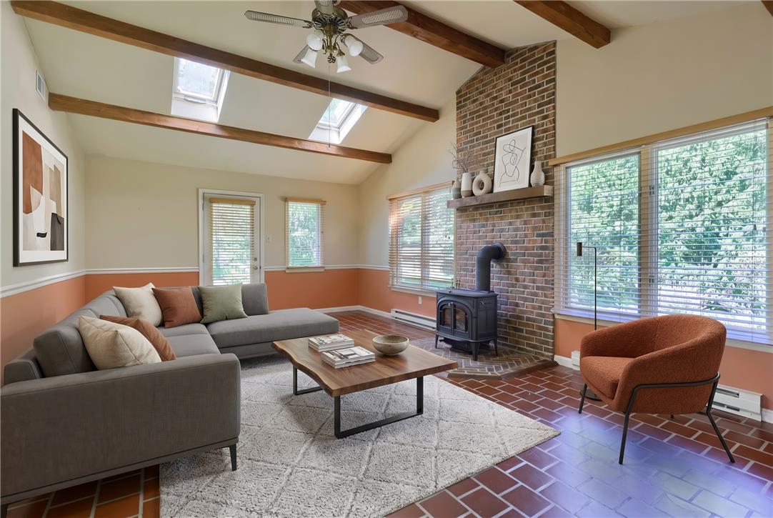 Coldsprings Rd Union Pottstown, PA 19465 - Photo 70 of 71 A well-lit living space features a cozy wood-burning stove and a brick accent wall, enhanced by exposed beams and skylights.