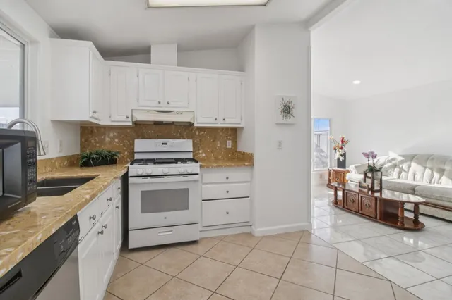 a kitchen with white cabinets a refrigerator and a stove