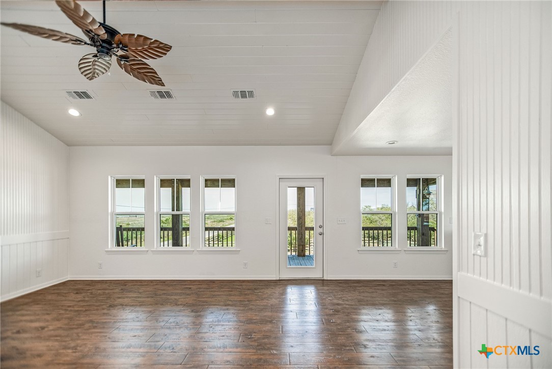 211 Taylor Avenue Port O'Connor, TX 77982 - Photo 25 of 43 an empty room with wooden floor chandelier fan and windows