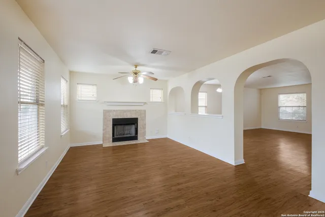 an empty room with wooden floor fireplace and windows