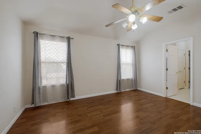 a view of an empty room with window and wooden floor