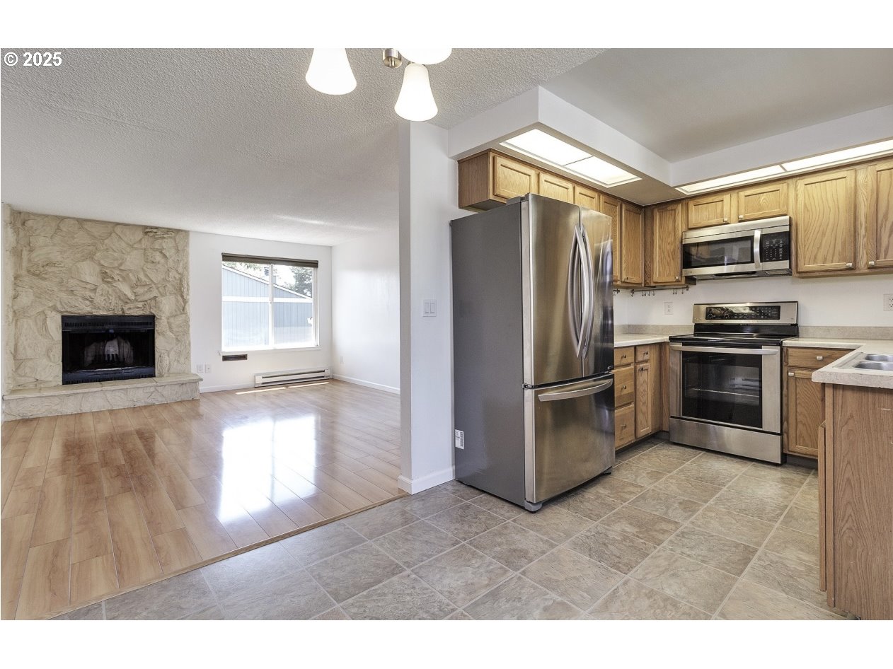 1470 Southeast Walnut Street, Unit 210 Hillsboro, OR 97123 - Photo 3 of 16 a kitchen with stainless steel appliances granite countertop a refrigerator a stove and a sink with cabinets