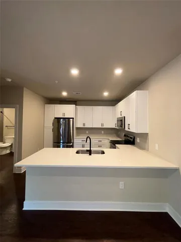 a large kitchen with kitchen island a sink a stove and a refrigerator with wooden floor