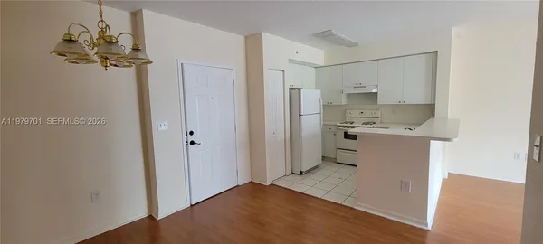 a view of a kitchen with a refrigerator a stove top oven and cabinets