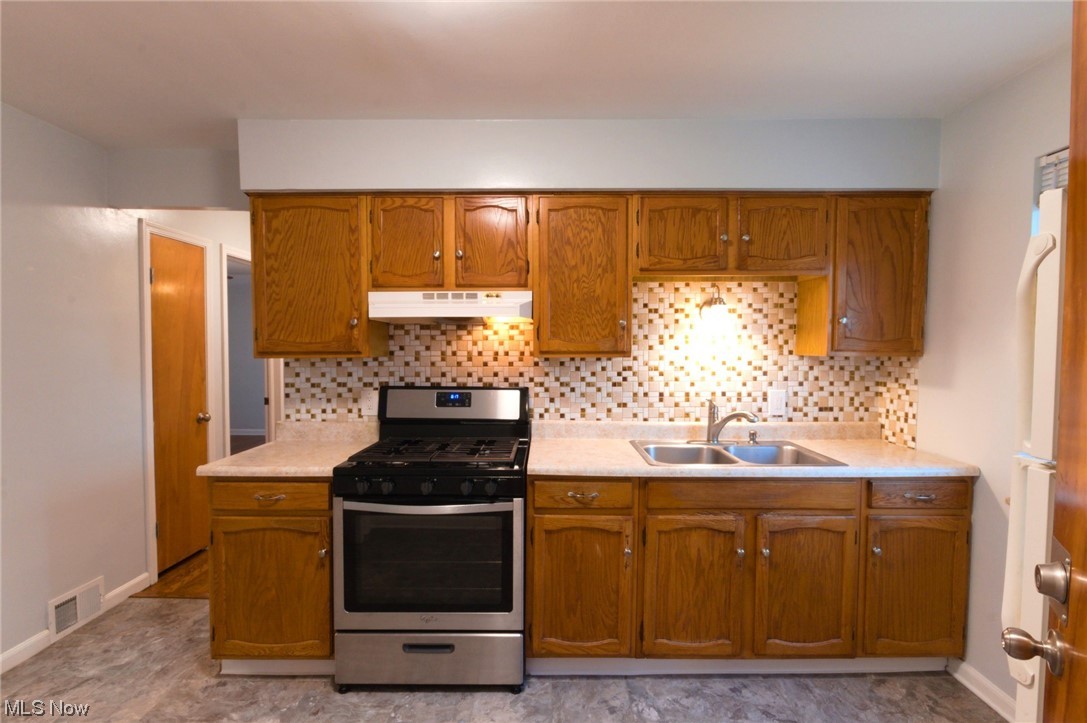 6462 Ridge Road Parma, OH 44129 - Photo 2 of 24 Kitchen featuring gas stove, white refrigerator, light tile flooring, backsplash, and sink