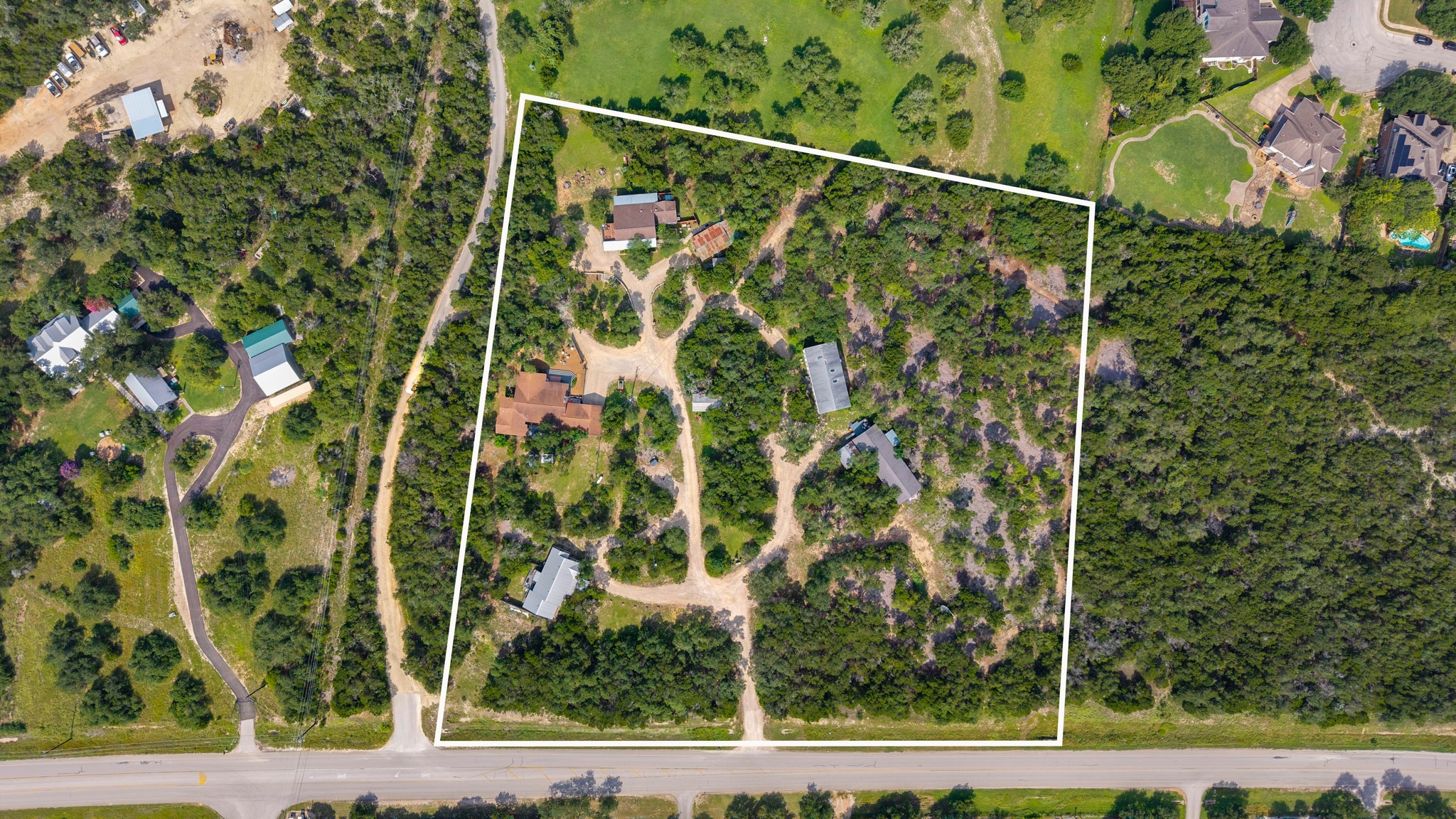 12932 Nutty Brown Road Austin, TX 78737 - Photo 1 of 40 Bird’s-eye view highlighting the property’s expansive grounds, multiple residences, and mature tree canopy.