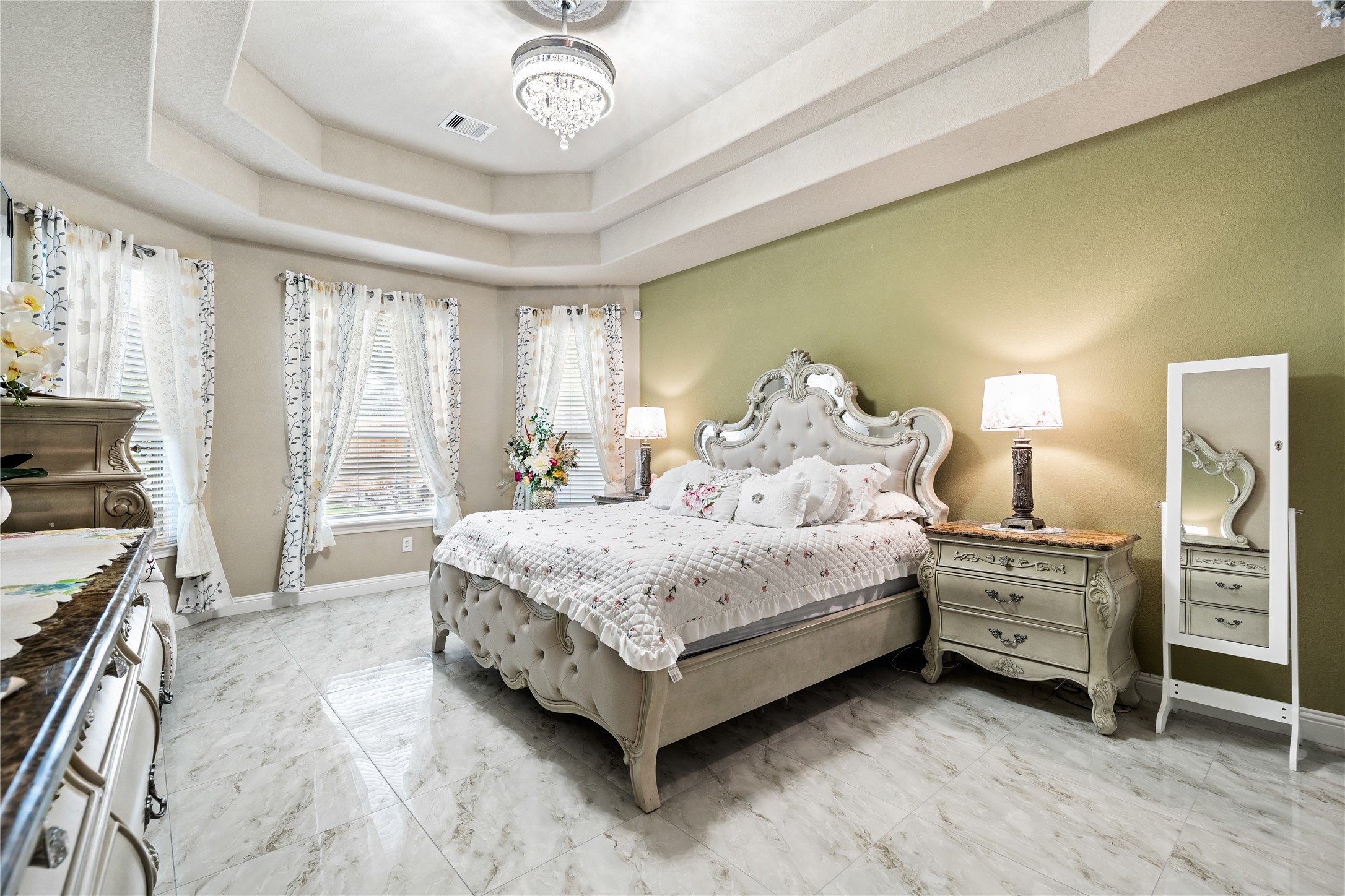 5802 Layton Meadows Lane Spring, TX 77379 - Photo 19 of 42 Master bedroom - wide shot showing the full room scale, windows flooding the space with natural light, marble floors, tufted bed, and nightstand.